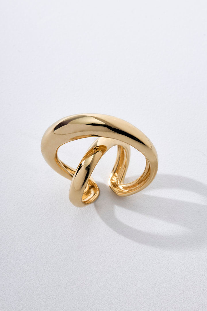 Anel Marea dourado com design vazado, linhas sinuosas cruzadas e acabamento polido.
