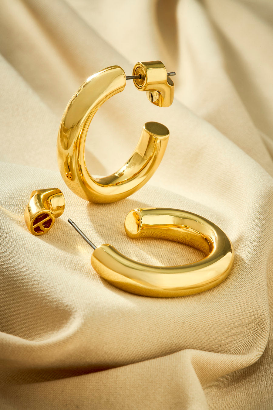 Brinco argola dourado pequena com design fluido e contemporâneo