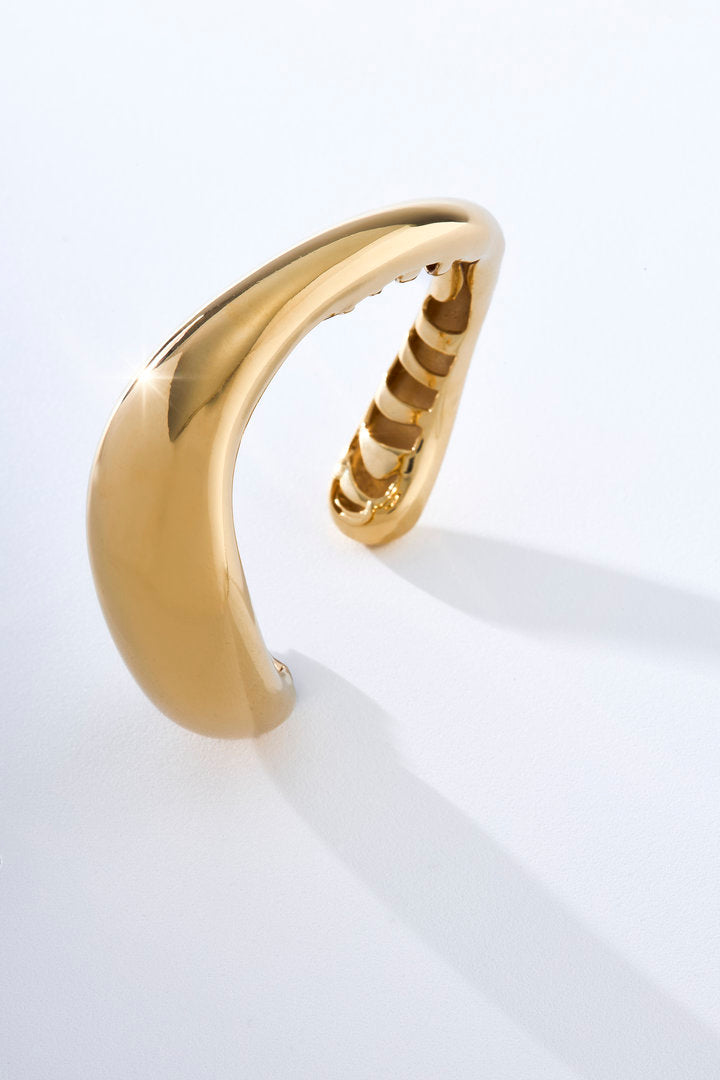 Bracelete Marea dourado de design orgânico e escultural, ideal para looks sofisticados e contemporâneos.