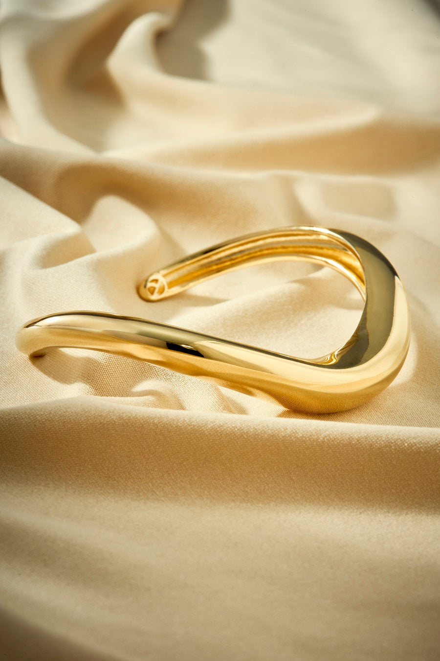 Bracelete autoral dourado com curva fluida e estética minimalista e visual elegante