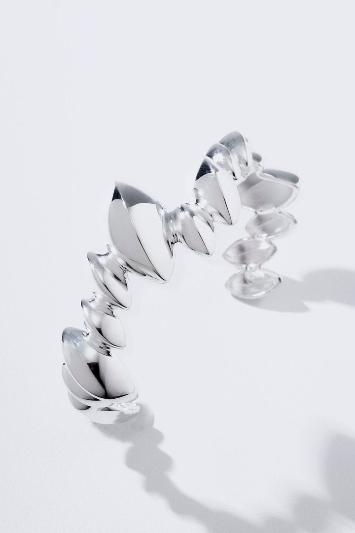 O Bracelete Trama traduz a leveza da natureza em uma joia de inspiração botânica. Com folhas estilizadas em movimento, acabamento polido e presença escultural, envolve o braço com brilho, harmonia e sofisticação.