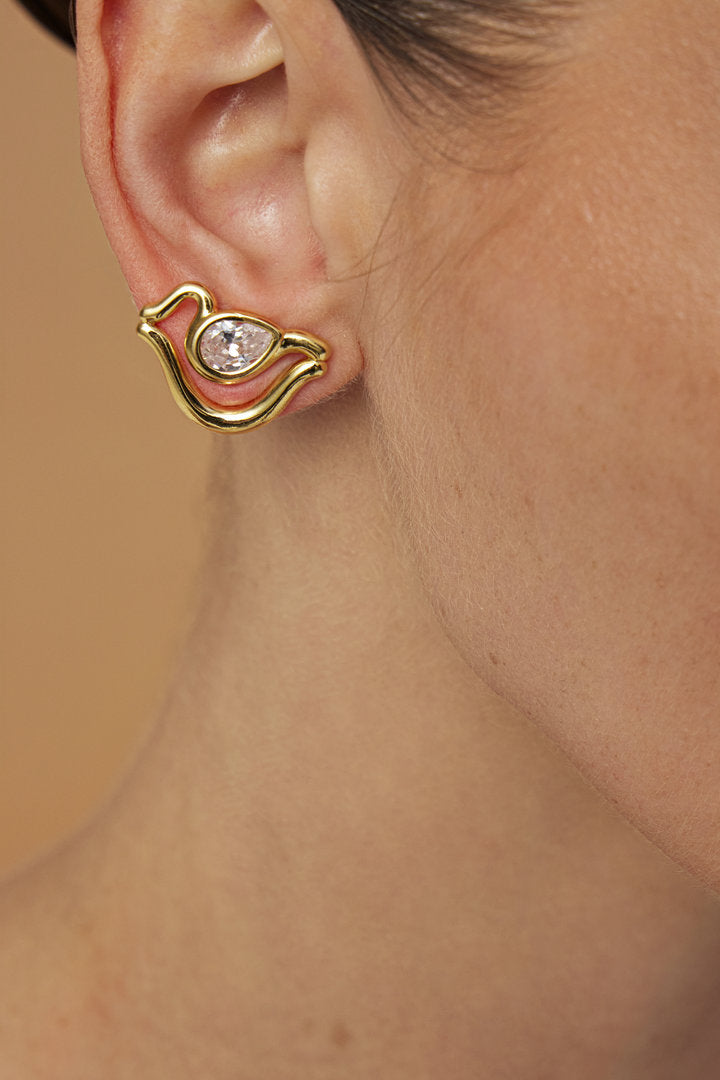 Brinco Audrey P em tom dourado com formas curvas e cristal lapidado em destaque