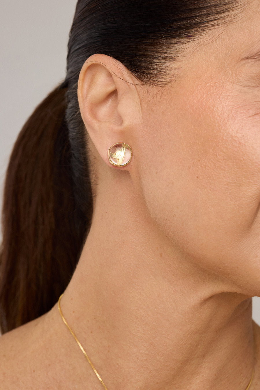 Brinco Duo Verde dourado com composição entre metal polido e cristal, unindo contraste suave e elegância contemporânea.