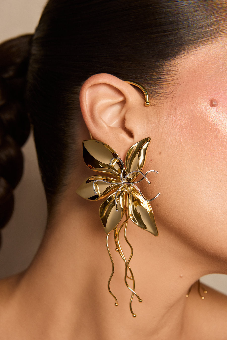 Brinco Renascer dourado – design autoral de flor com volumes orgânicos e fios fluidos alongados