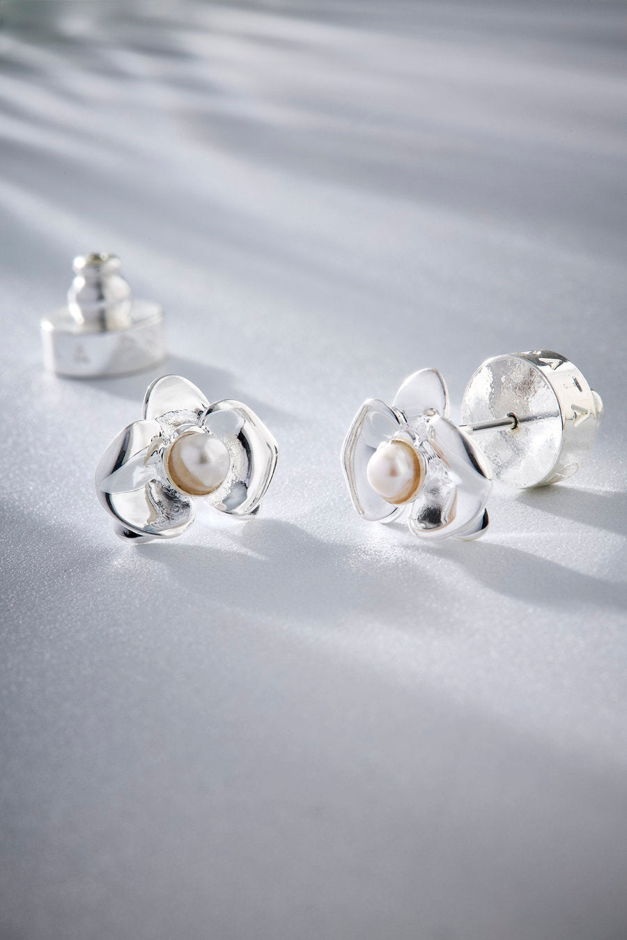 Brinco Florescer prata com design floral escultural e detalhe central delicado, ideal para presentear com elegância.