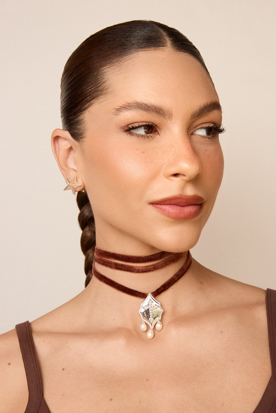 Choker Autoridade dourada com fita de veludo preta, pingente ornamental e pérolas, usada em composição fashion feminina.