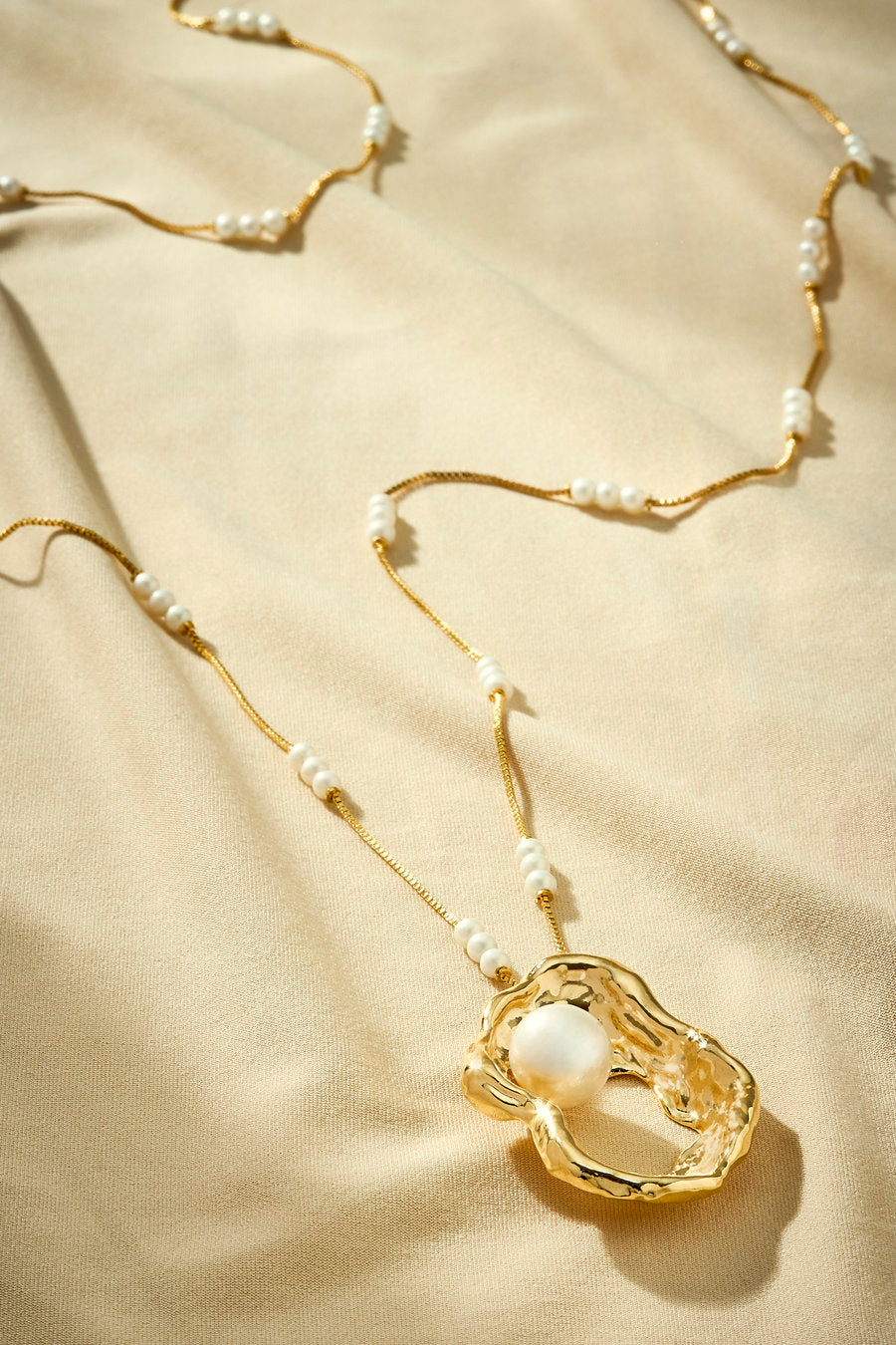 Colar longo dourado com pérolas e pingente orgânico escultural