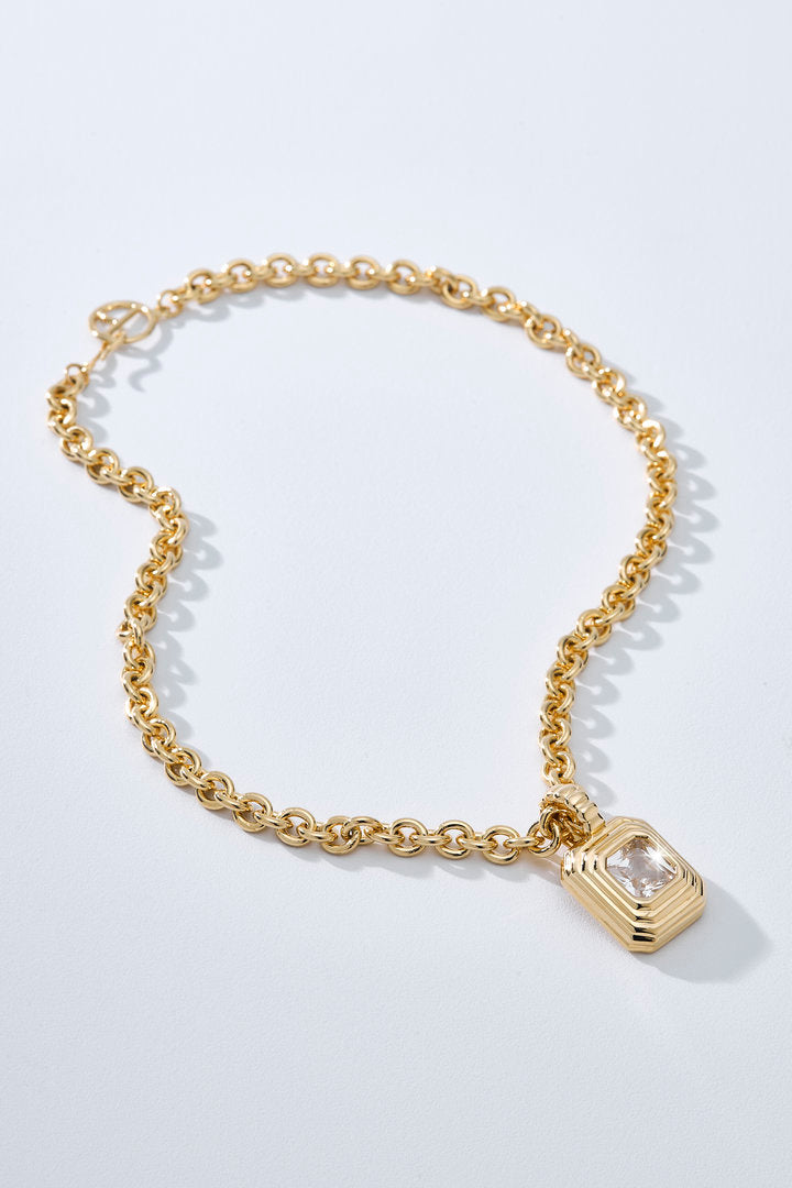 Colar Lumier dourado com corrente de elo redondo e pingente geométrico retangular texturizado com zircônia central.