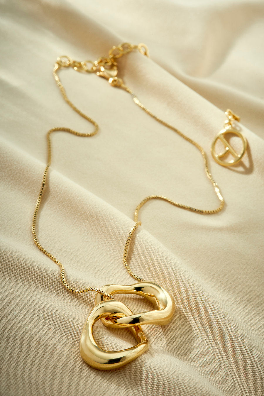 Colar dourado com pingente de elos orgânicos entrelaçados