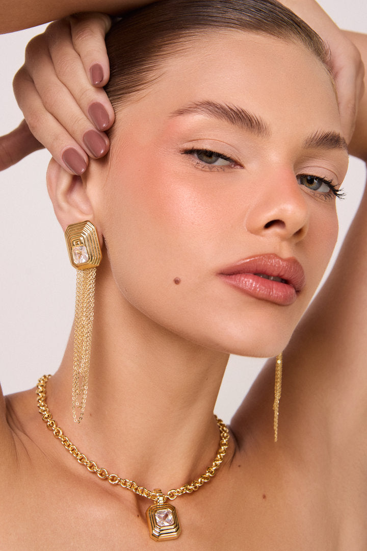 Colar Lumier dourado com pingente geométrico e zircônia central, ideal para looks elegantes, modernos e versáteis.