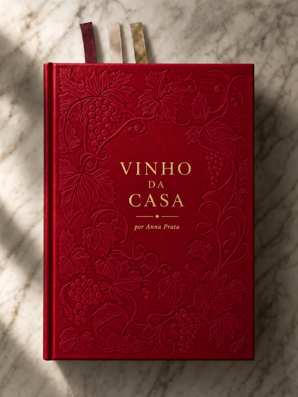 Capa do Livro Vinho da Casa, de Anna Prata, devocional cristão e planner anual, com capa dura, uvas e videiras em relevo, letras douradas e três fitas marcadoras.