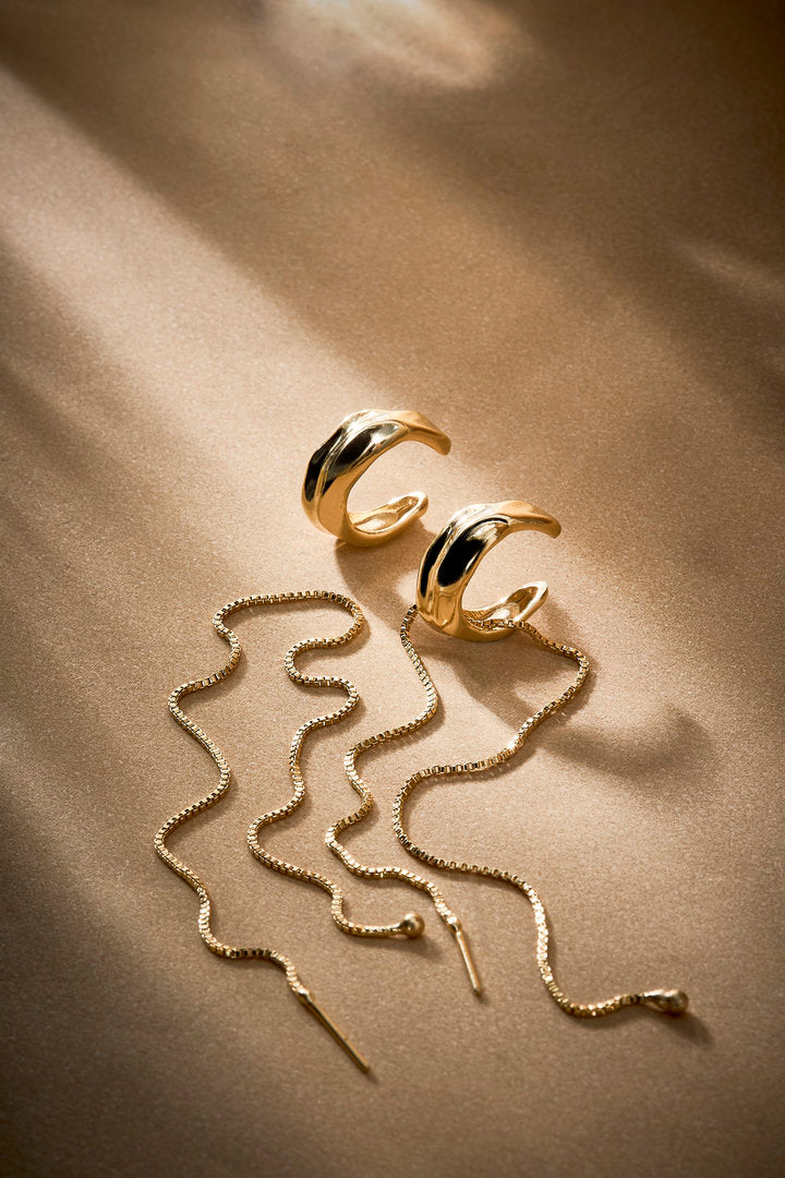 Piercing Frida dourado com correntes fluidas, design statement para produções sofisticadas