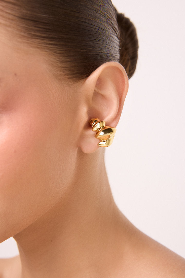 Piercing Trama dourado com design botânico escultural e acabamento polido, ideal para composições modernas e sofisticadas.