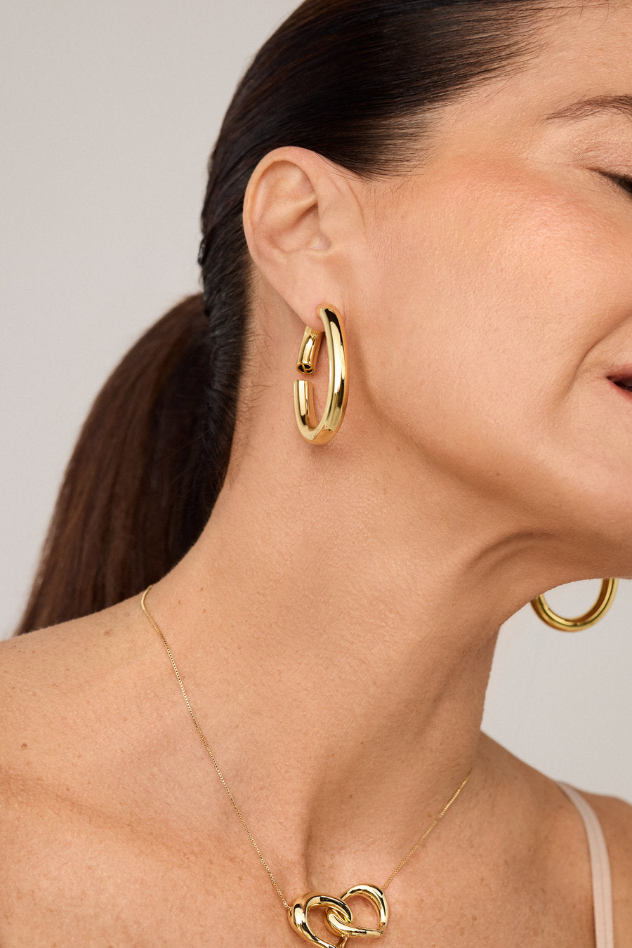 Brinco argola dourado com curvas suaves e acabamento polido