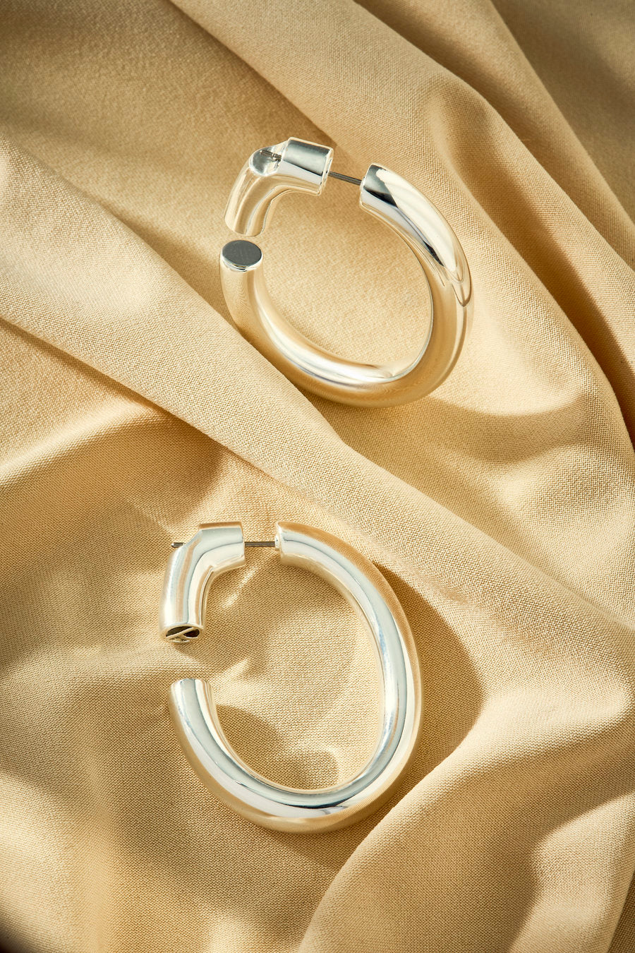 Argola prata grande com formato curvo e visual minimalista