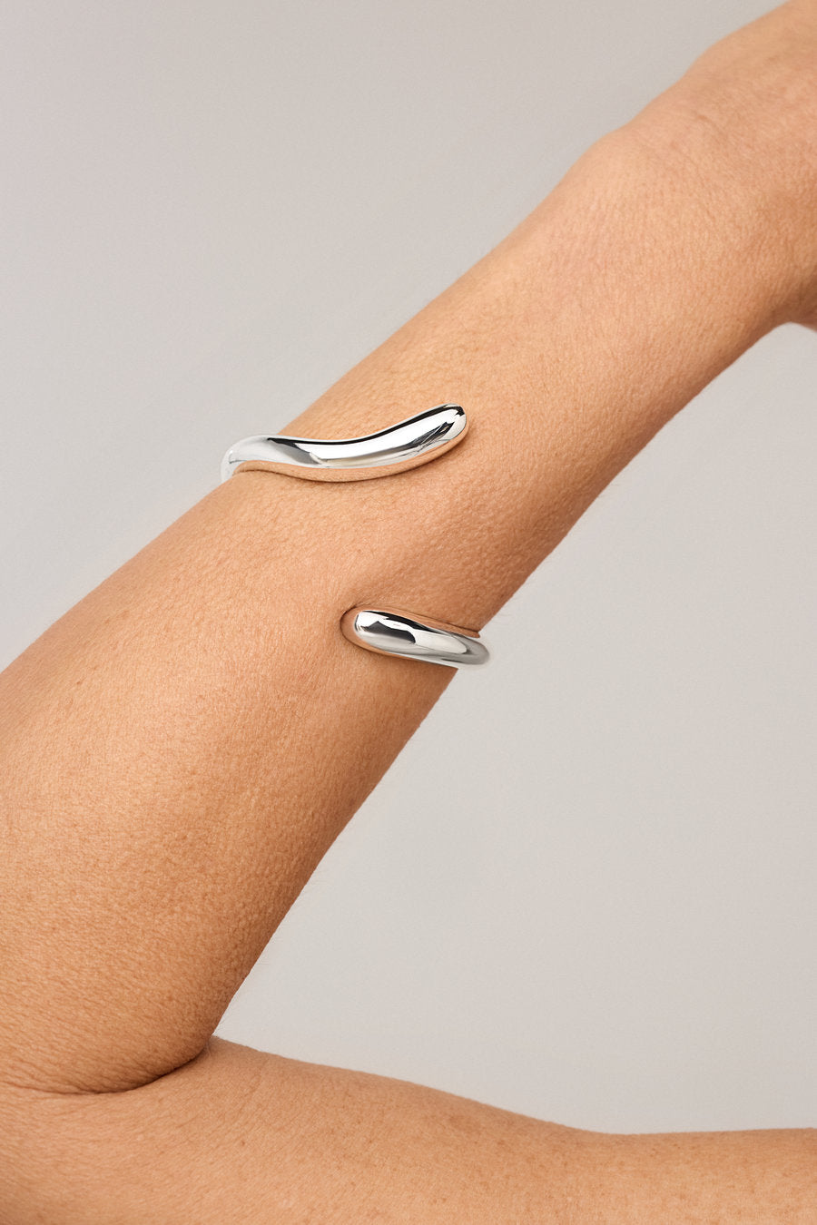 Bracelete feminino prata com design escultural fluido e acabamento polido