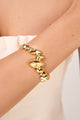 Bracelete Trama dourado com design aberto, folhas estilizadas em sequência e acabamento polido sobre fundo claro.