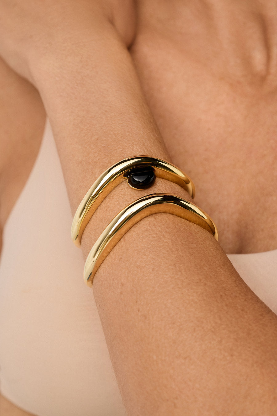 Bracelete autoral dourado com pedra negra e curva fluida elegante