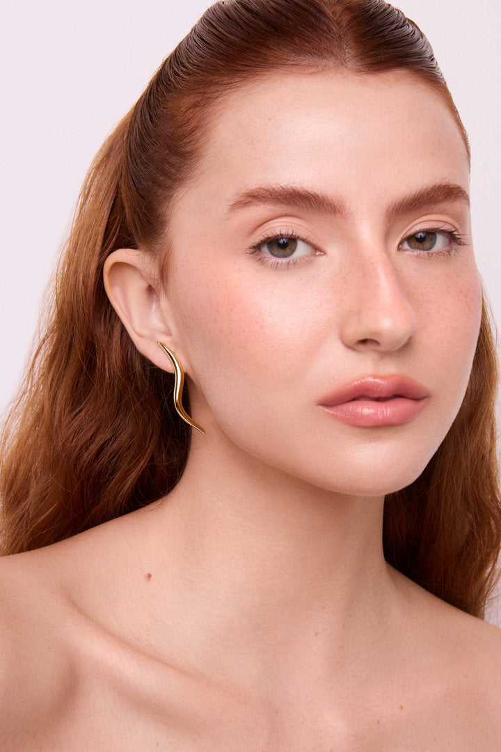 Brinco escultural em dourado e prata com curvas orgânicas e visual contemporâneo