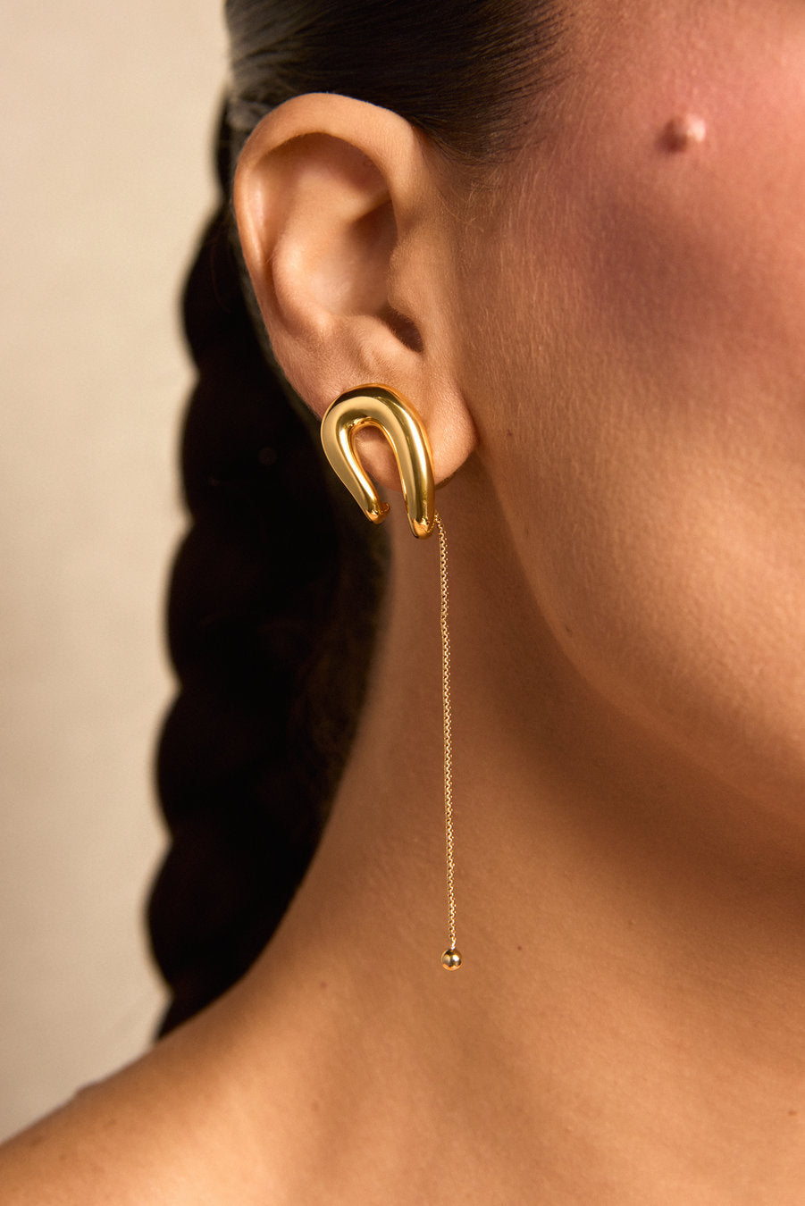 Brinco Delicata P dourado – design minimalista com curvas sobrepostas e corrente em movimento