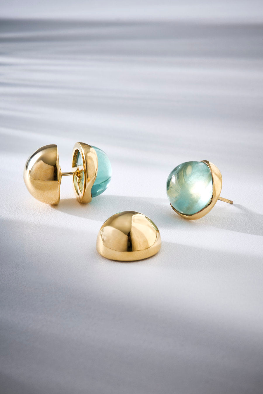 Brinco Duo Verde dourado com composição entre metal polido e pedra verde translúcida, unindo contraste suave e elegância contemporânea.