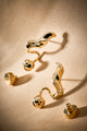 Brinco Frida dourado com formas fluidas, joia statement para produções elegantes.