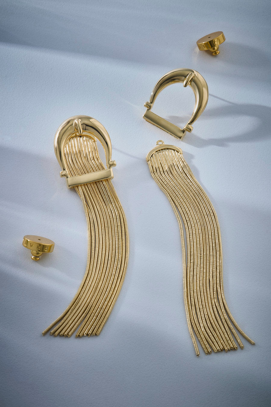 Brinco dourado longo com topo em arco escultural e franjas de correntes finas com acabamento polido.