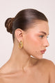 Brinco Marea dourado com design orgânico entrelaçado, visual escultural e brilho sofisticado para composições elegantes.