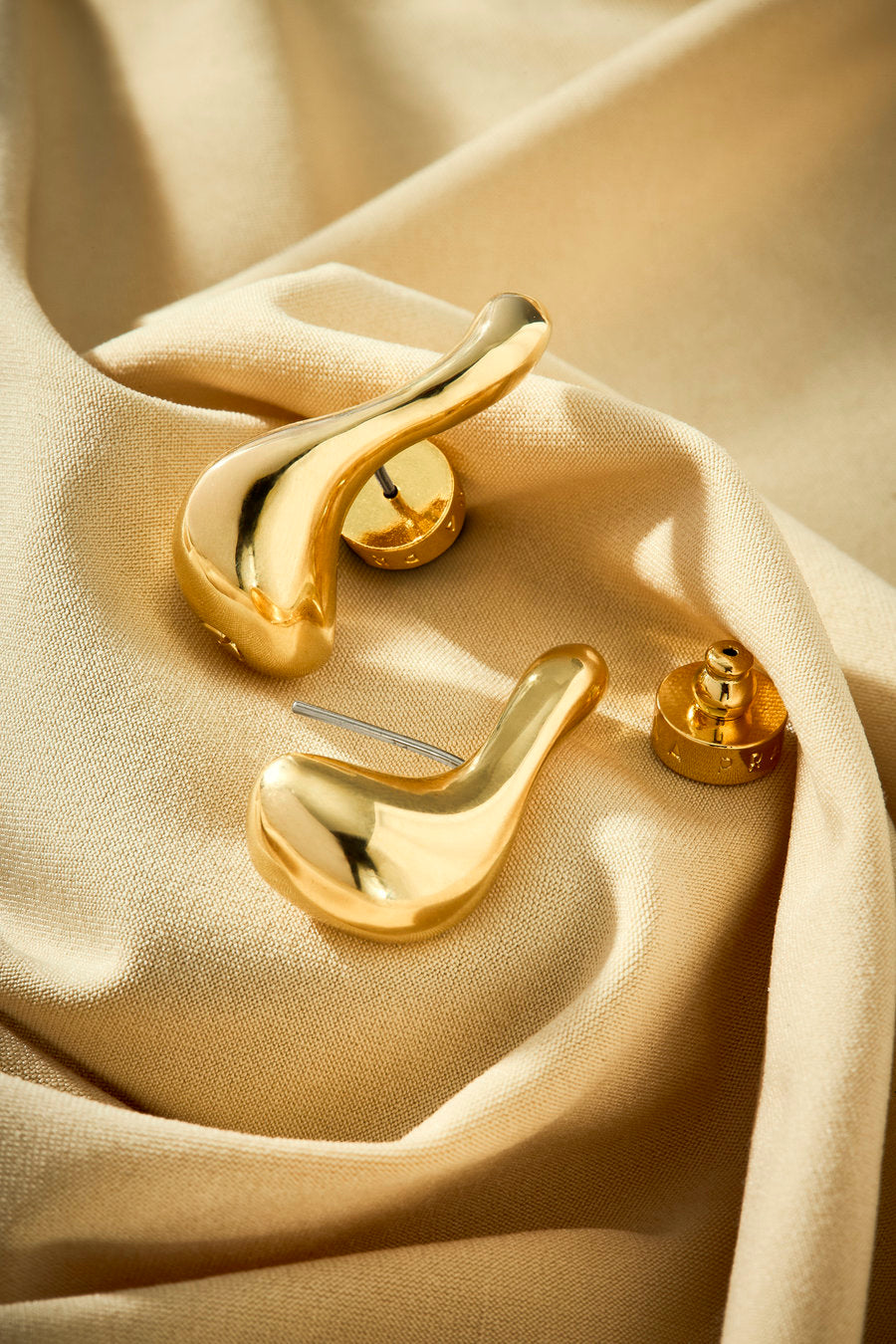Brinco dourado contemporâneo com linhas fluidas e visual elegante
