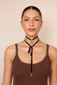 Gargantilha choker de veludo preto com medalhão dourado e pérolas pendentes, acessório elegante e marcante para o pescoço.