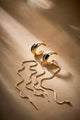 Piercing Frida dourado com correntes fluidas, design statement para produções sofisticadas
