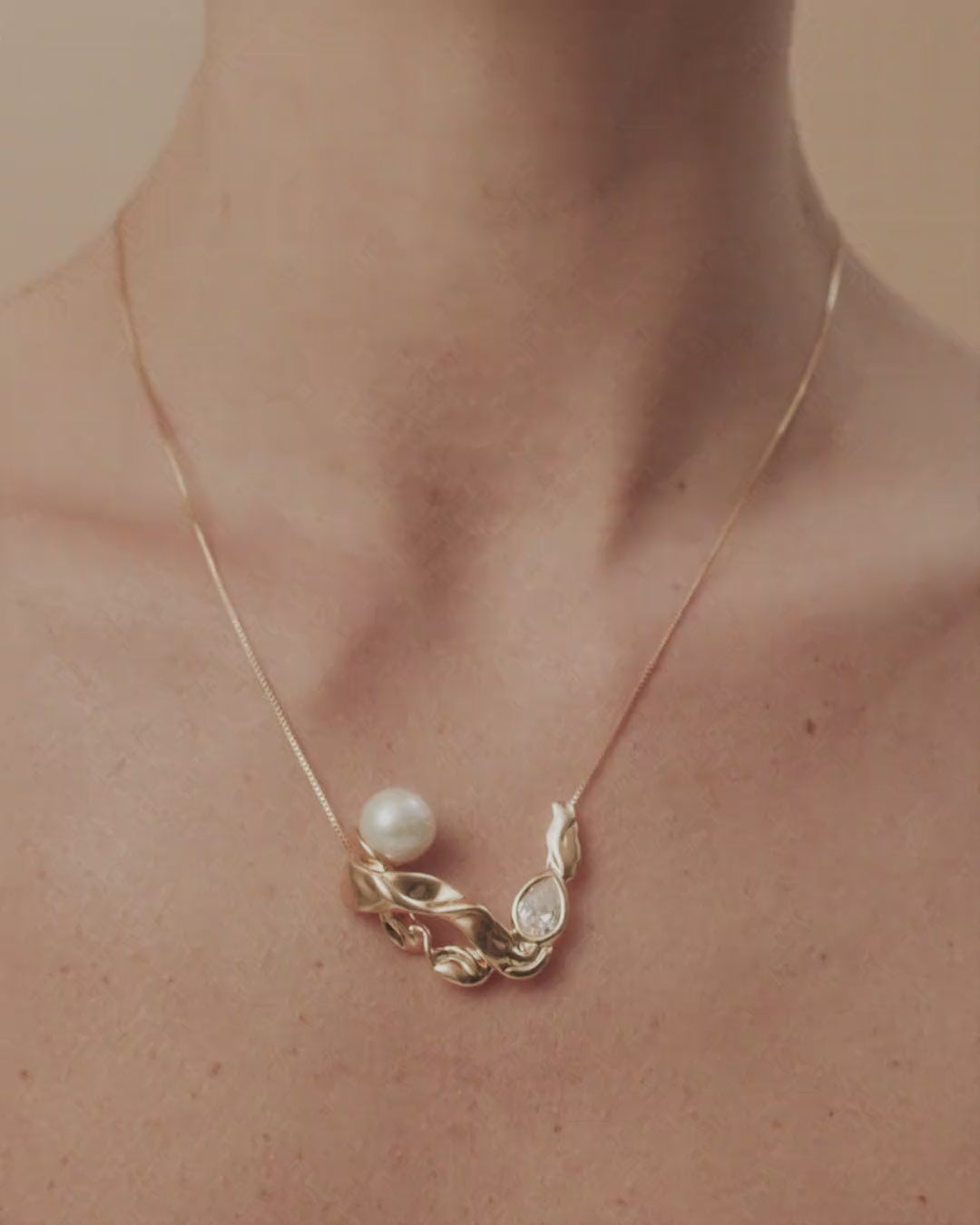 Colar Audrey dourado e prata com pérola, cristal austríaco e formas fluidas que evocam o encanto do cinema clássico.